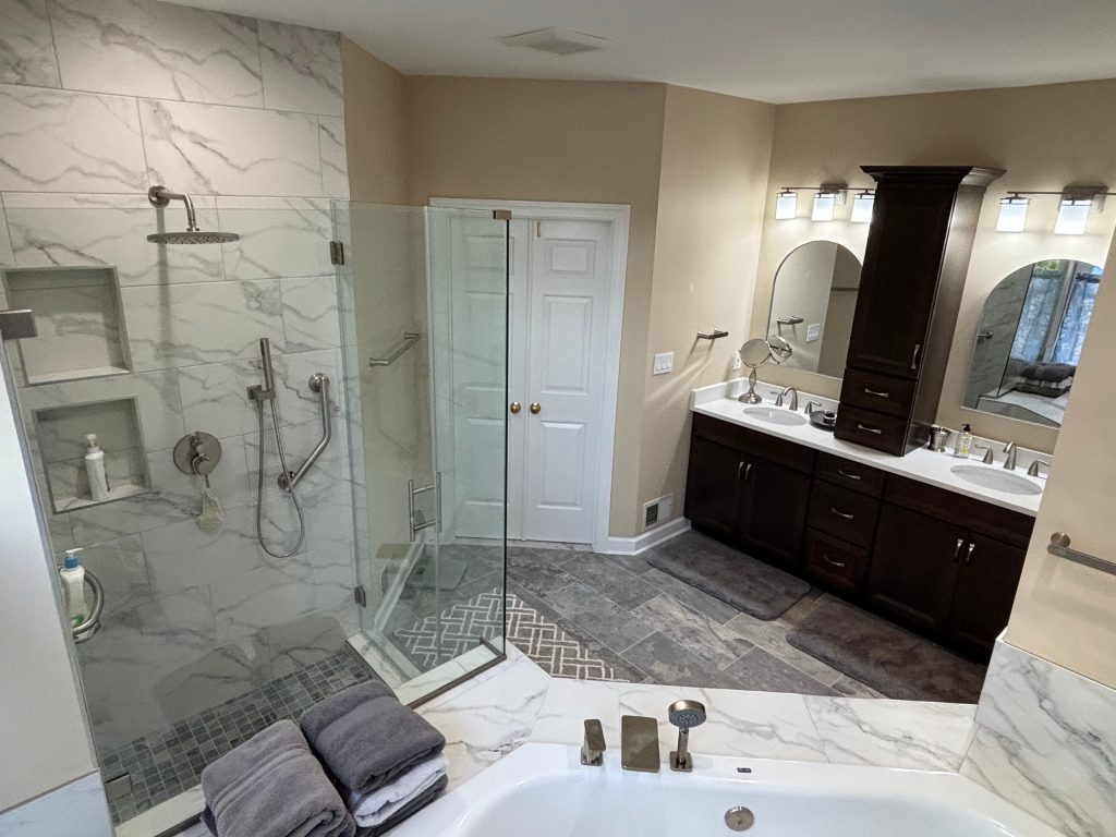 The bathroom after remodeling, with a marble walk-in shower and a dark double vanity