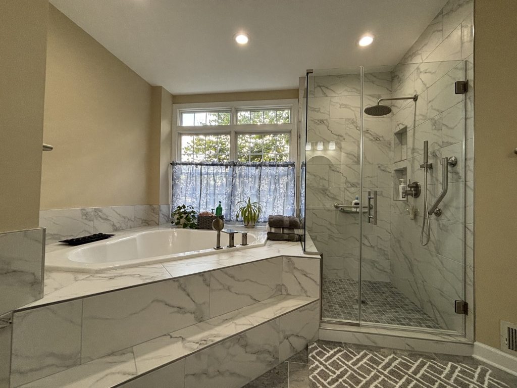 Primary bathroom remodel with a marble tub deck and a frameless glass shower