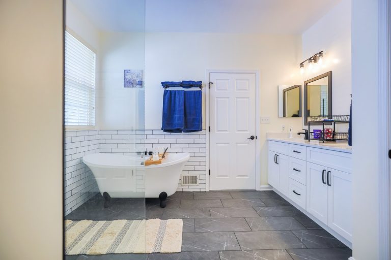 Remodeled bathroom with a clawfoot tub, subway tile wainscot and a white double vanity
